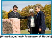 A young man and an older adult couple gazing at a headstone (Staged with professional models).