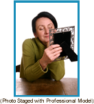 Woman gazing at a photo in a picture frame. (Staged with a professional model).