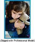 Sad little girl with pony tails hugging a teddy bear.