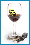 Wine glass with a small yellow toy car partially submerged in the partially filled glass with a set of car keys placed at the bottom of the glass.